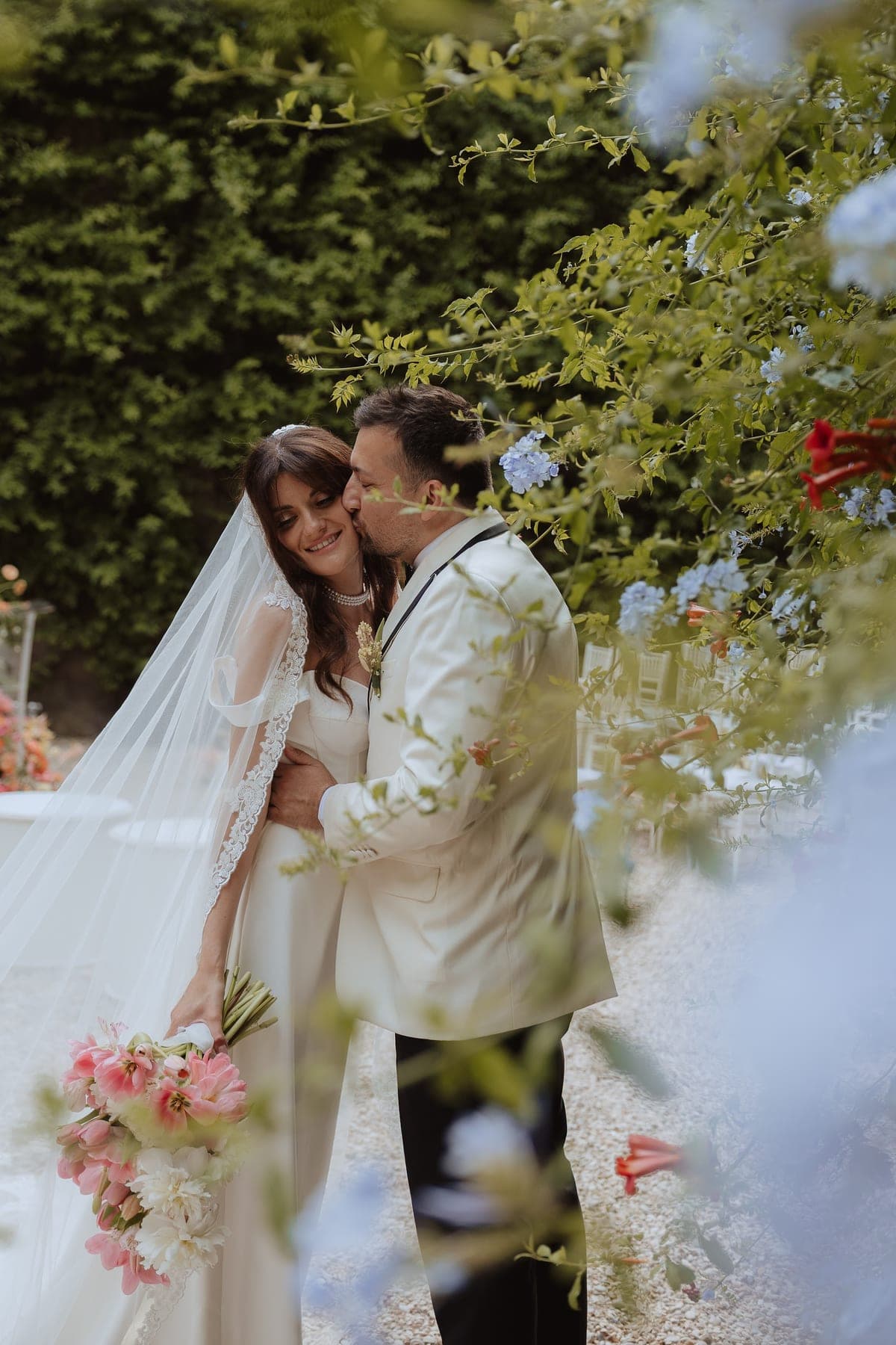 Gli sposi si baciano in giardino, tra i fiori