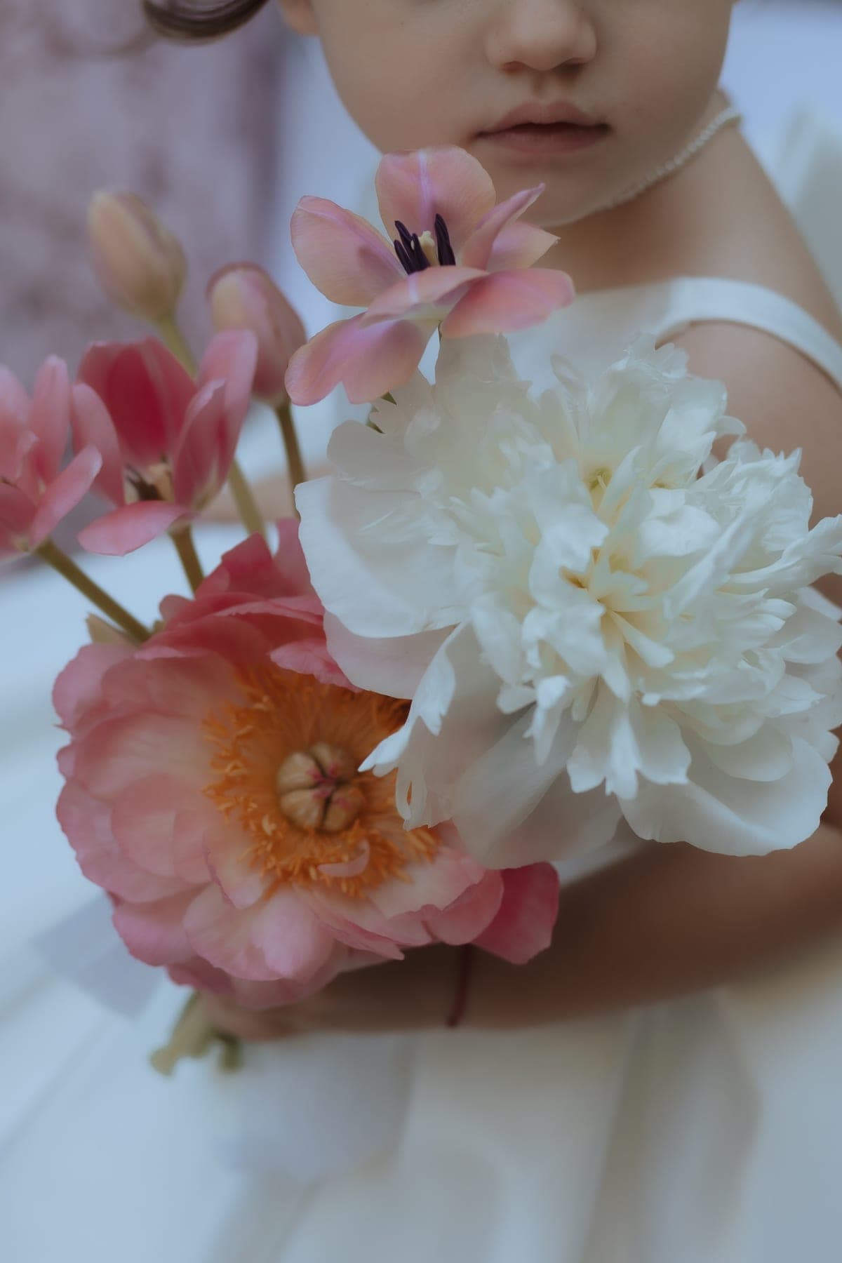 Bambina con un bouquet di peonie